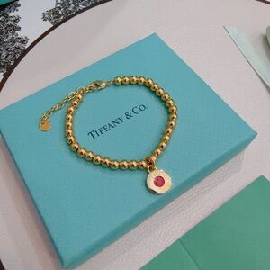 Elegant Gold Bracelet with Red Charm by Tiffany & Co.